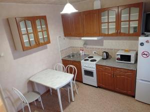 a kitchen with a table and a stove and a refrigerator at 1к. Апартаменты НСК на ул.Блюхера 67/1 in Novosibirsk