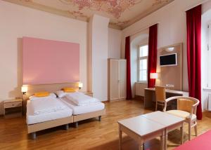 a hotel room with two beds and a table at CMA Stift Ossiach in Ossiach +49 photos