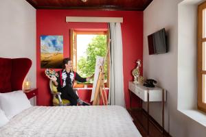 une femme assise sur une chaise dans une pièce rouge dans l'établissement A for Art Hotel, à Thasos