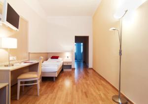 a hotel room with a bed and a desk and a computer at CMA Stift Ossiach in Ossiach