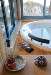 una bottiglia di whisky seduta su un tavolo accanto a una vasca di Darna Bagalil Merlot suite Perfect for couples a Lavon