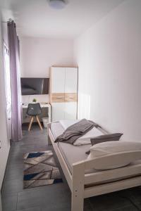 a white bedroom with a bed and a chair at Hotel Schenk in Pirmasens