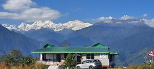 a car parked in front of a building with mountains in the background at Hotel Snow Valley Rooftop in Pelling