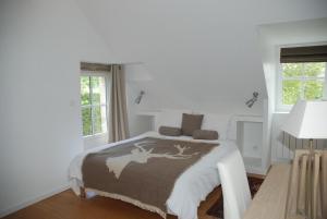 a white bedroom with a bed and two windows at Le Pavillon de la Lanterne in Rochecorbon