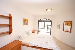 a white bedroom with a bed and a window at Casa Ronda in Charco del Palo