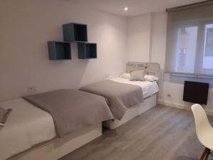 a small bedroom with two beds and a tv at Apartamento Ángela in Gijón