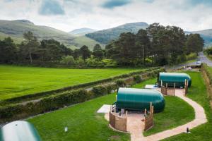 two large green tanks in a field next to a road at Further Space at Leitrim Lodge Luxury Glamping Pods Mourne Mountains in Newcastle