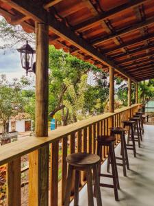 a row of stools on a deck with trees at Vila Sancar Pousada in Lençóis