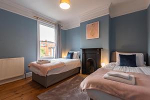 a bedroom with two beds and a fireplace at Cosy 2 Bedroom Reading House SLEEPS 6 - With FREE WiFi & Garden by Roost Accommodation in Reading
