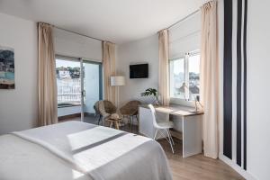 a hotel room with a bed and a desk and windows at Hotel Terramar in Llafranc