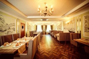 um restaurante com mesas e cadeiras longas e um lustre em Marko Polo Hotel em Aksay