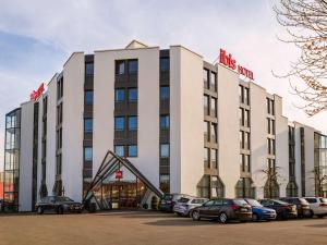 un bâtiment avec des voitures garées dans un parking dans l'établissement ibis Lausanne Crissier, à Lausanne