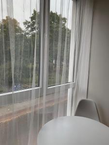 a window with white curtains and a white table and chair at Appartements in der Kornstraße in Bremen