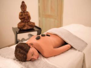 a woman laying on a bed with her head on a towel at Almar Timi Ama Resort & Spa in Villasimius