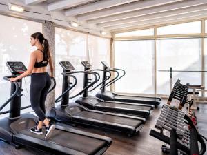 a woman walking on a treadmill in a gym at Almar Timi Ama Resort & Spa in Villasimius
