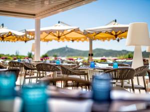 a group of tables and chairs with yellow umbrellas at Almar Timi Ama Resort & Spa in Villasimius