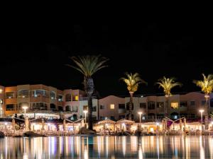 a resort with palm trees and a swimming pool at night at Almar Timi Ama Resort & Spa in Villasimius