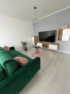 a living room with a green couch and a flat screen tv at Apartament Bella in Târgu-Mureş