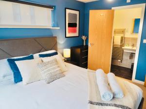 a bedroom with a white bed with blue walls at Stylish New Build with Garden and Free Parking in Taunton