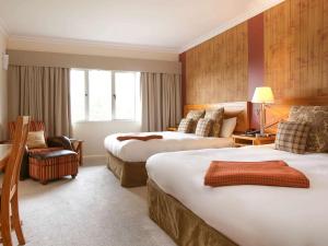 um quarto de hotel com duas camas e uma cadeira em Fairmont Resort & Spa Blue Mountains MGallery by Sofitel em Leura