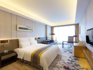 ChangshuにあるPullman Changshu Leemanのベッドとテレビが備わるホテルルームです。
