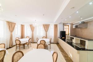 a dining room with tables and chairs and a kitchen at Ilinka Hotel in Vladimir