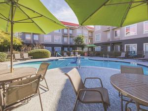a pool with tables and umbrellas at a hotel at La Quinta by Wyndham Austin at The Domain in Austin
