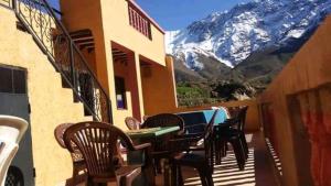 balcone con tavolo, sedie e montagna di Gite Dar Tanzoughte a Imlil