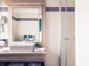 La salle de bains est pourvue d'un lavabo et d'un miroir. dans l'établissement Mercure Villeneuve Loubet Plage, à Villeneuve-Loubet