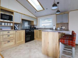 a kitchen with wooden cabinets and a black stove top oven at Beachcliff in Newquay