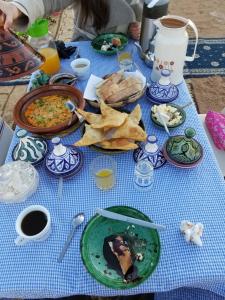 a blue table topped with plates of food and chips at Family Moroccan House in Merzouga