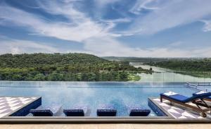 a swimming pool with chairs and a view of a river at Taj Lakefront Bhopal in Bhopal