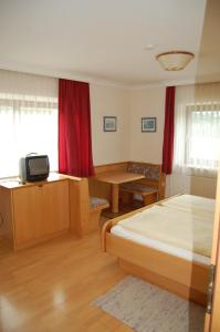 a bedroom with a bed and a table and a tv at Gasthof Grabenwirt in Irdning