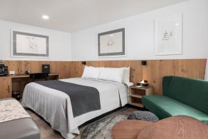 ソノラにあるHotel Lumberjack - Sonoraのベッドと緑のソファが備わるホテルルームです。