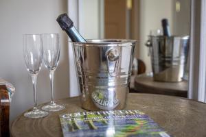 a metal bucket with a toothbrush in it next to two glasses at The Running Horses in Mickleham