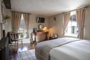 a bedroom with a bed and a chair and windows at The Running Horses in Mickleham