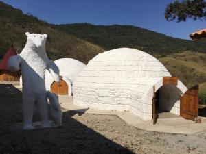 um grande urso de peluche branco parado em frente a um iglu em Hotel Fazenda Morada dos Deuses em Paraibuna