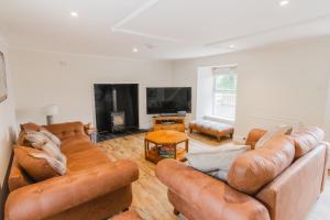 a living room with brown leather couches and a tv at Dalnaglar Castle Estate in Glenshee