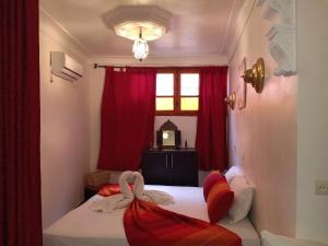 a bedroom with a bed with red curtains and a window at Dar HAJAR in Marrakech
