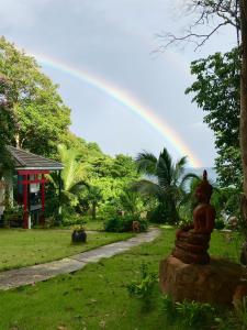 een regenboog in de lucht boven een tuin met een standbeeld bij Jasmin Garden Koh Kood in Ko Kood