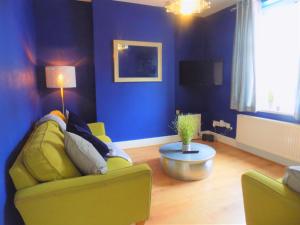 uma sala de estar com um sofá amarelo e uma parede azul em The Railway House em Cardiff