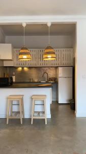 une cuisine avec deux tabourets, un comptoir et deux lumières dans l'établissement Porto Covo Bay House, à Porto Covo