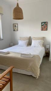 - une chambre avec un grand lit et des draps blancs dans l'établissement Porto Covo Bay House, à Porto Covo