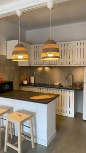 - une cuisine avec deux lampes suspendues et un comptoir dans l'établissement Porto Covo Bay House, à Porto Covo