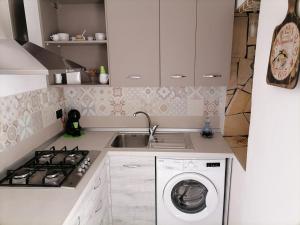 uma cozinha com um lavatório e uma máquina de lavar roupa em Casa Milena em Siracusa
