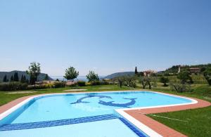a large swimming pool in a field with a hill in the background at Appartamenti I Cortivi in Costermano