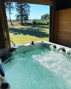 a jacuzzi tub with a view of a yard at Kourline Villalunoterie Futuroscope Piscine spa in Oyré