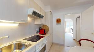 uma cozinha com armários brancos, um lavatório e um fogão em Plattas 9 em St. Moritz