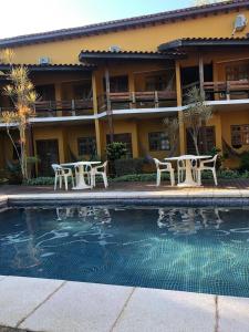 ein Hotel mit Tischen und Stühlen neben einem Pool in der Unterkunft Pousada In Bali - Maresias in Maresias