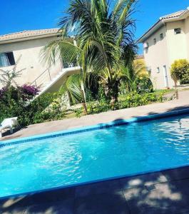 een zwembad voor een huis met een palmboom bij Il Pevero Condominio AC in Porto Seguro